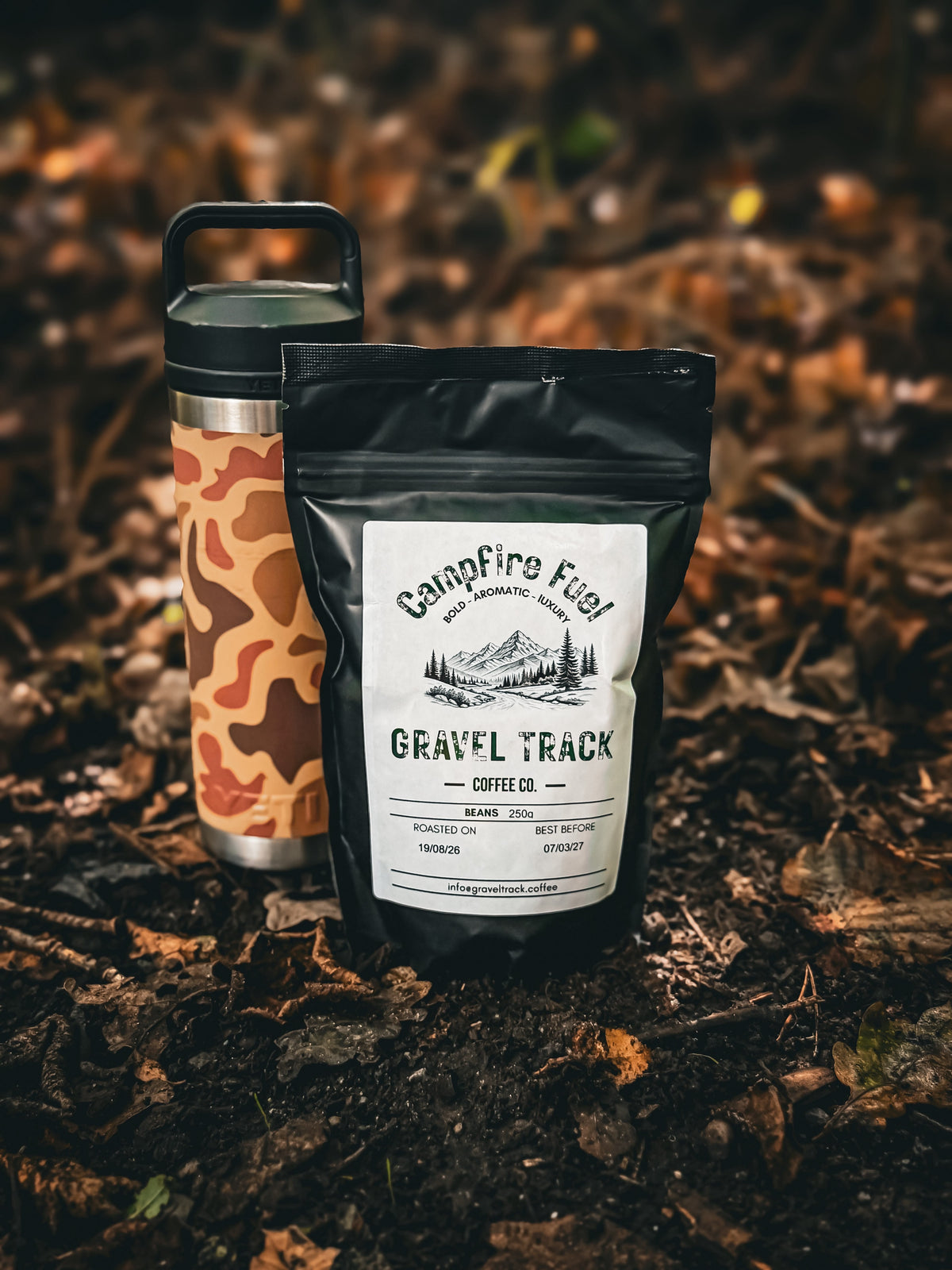A circular vintage-style coffee label or sticker design featuring an off-road vehicle on a mountain road, with the text 'GRAVEL TRACK COFFEE CO.' and 'ENPLORE FURTHER • BREW STRONGER'.